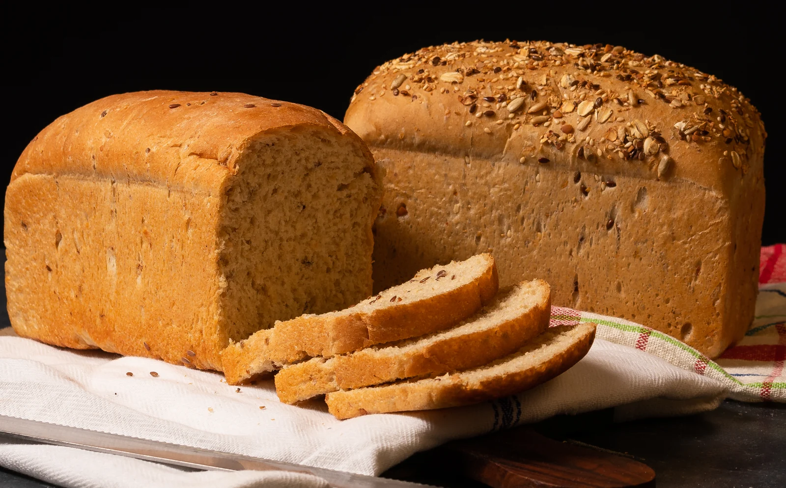 Two bread loaves with sliced bread on a board