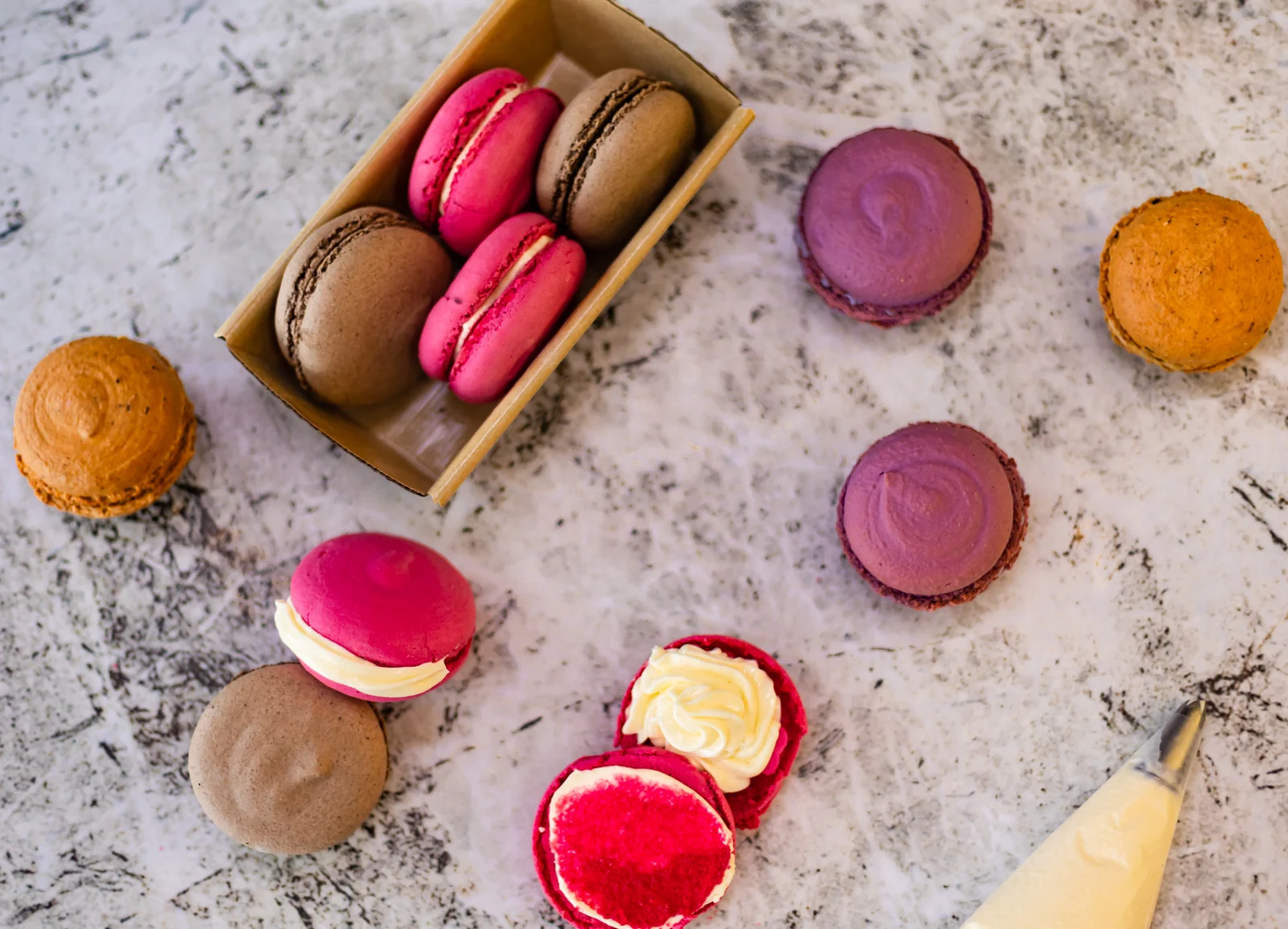 Colourful macarons with cream filling and a piping bag