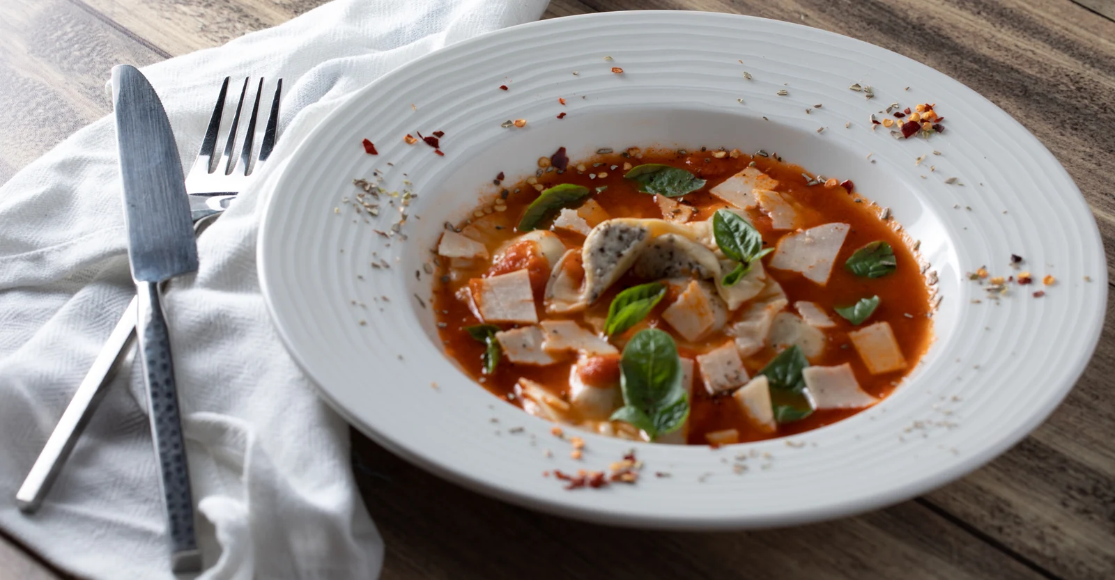 Ravioli in sauce with basil leaves and cheese shavings